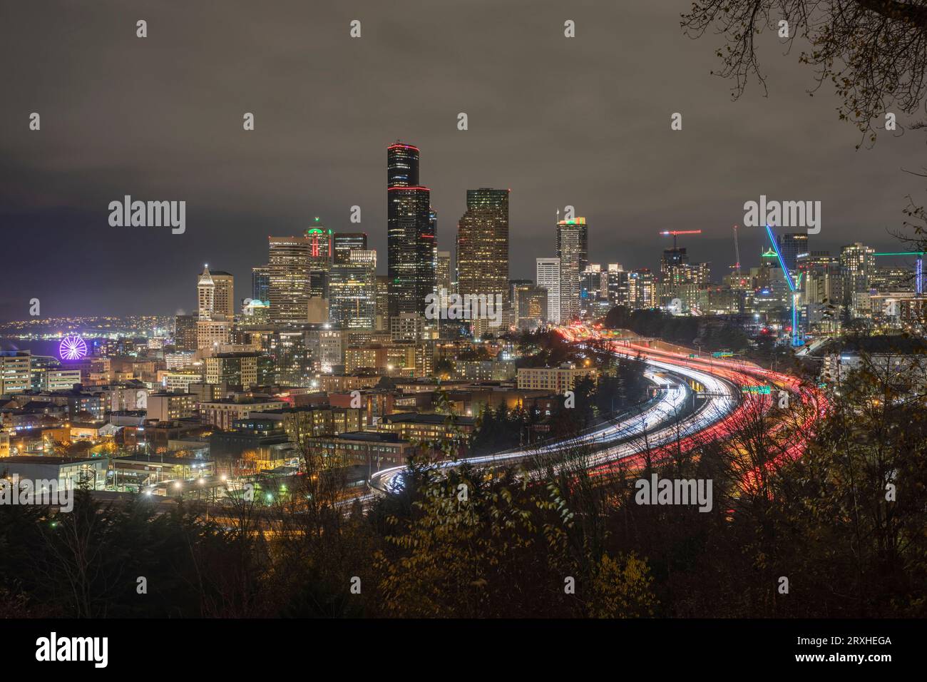 Vista notturna dello skyline di Seattle con traffico sulla i-5 e la grande ruota panoramica di Seattle all'estrema sinistra; Seattle, Washington, Stati Uniti d'America Foto Stock