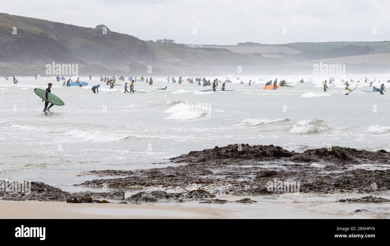Bodyboarders e surfisti in mare con spruzzi e nebbia soffiati dal vento. Foto Stock