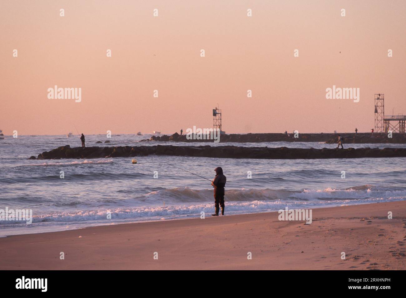 Fisherman surf casting sulla spiaggia di Avon by the Sea, New Jersey, sulla costa del New Jersey all'alba Foto Stock