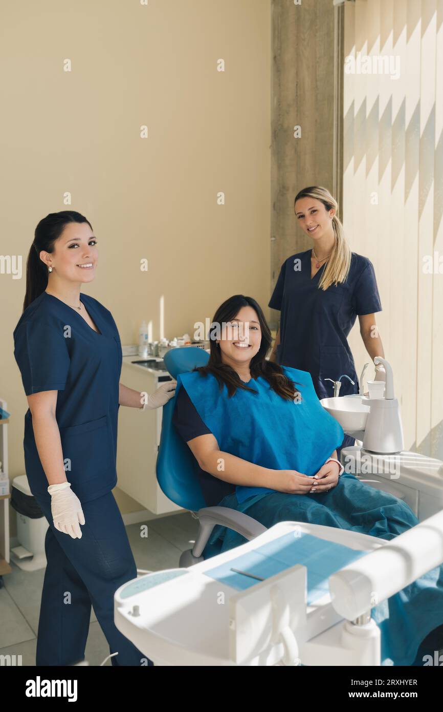 Ritratto di tre donne, dentista, assistente e paziente in uno studio odontoiatrico che sorridono e guardano la macchina fotografica. Concetto di salute dentale. Foto Stock