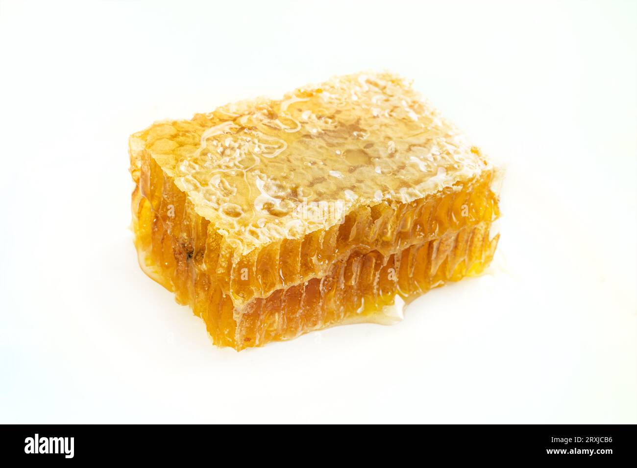 Pezzo a nido d'ape. Fetta di miele isolata su sfondo bianco. Elemento di design del contenitore. Primo piano a nido d'ape fresco Foto Stock