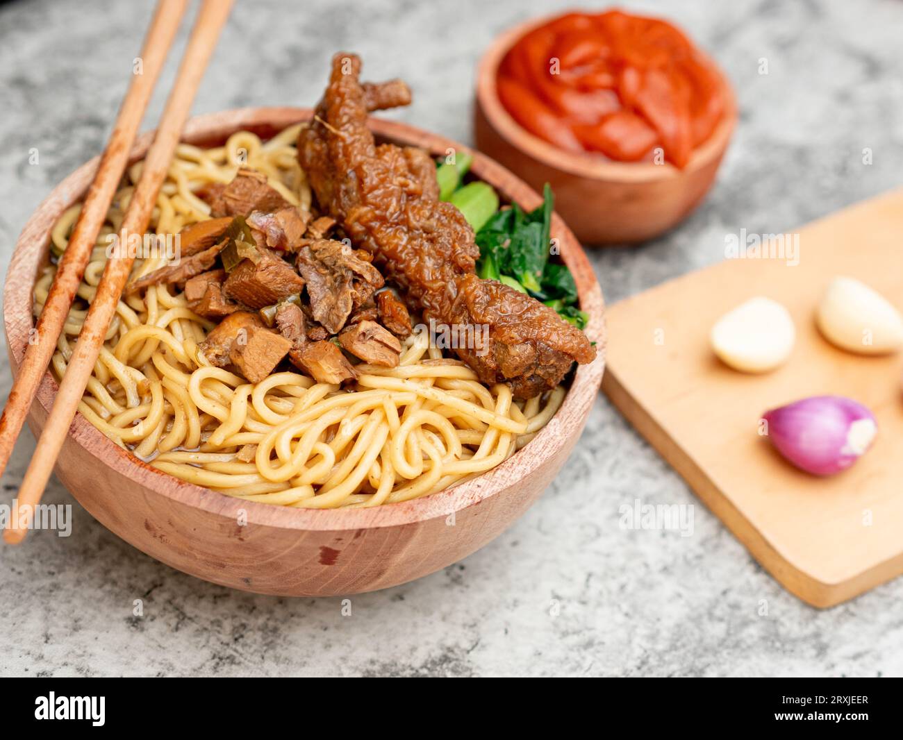 Spaghetti di pollo indonesiani chiamati mie ayam conditi con carne di pollo e senape verde serviti in una ciotola con salsa rossa speziata Foto Stock