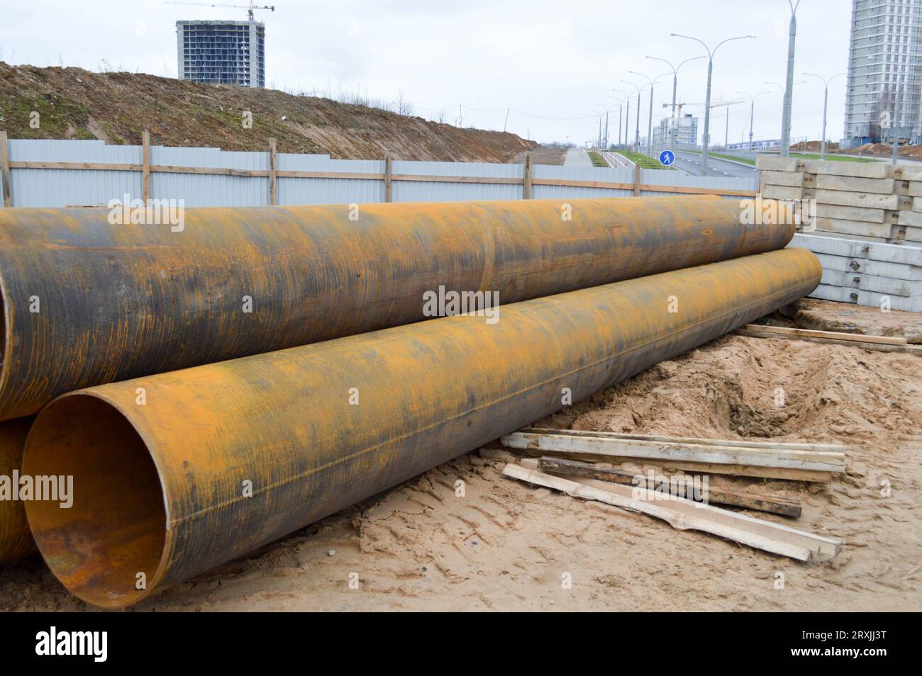 Tubi idraulici in metallo di ferro di grandi dimensioni di grande diametro per la costruzione industriale di approvvigionamento idrico o fognature in un cantiere di costruzione durante il re Foto Stock