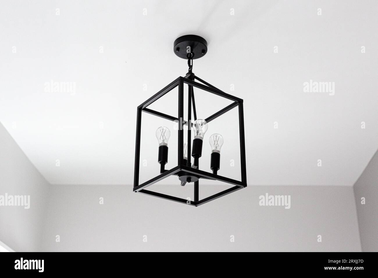 Moderno impianto di illuminazione per fattorie nero con forma geometrica del cubo e lampadine. Soffitto bianco vuoto Foto Stock