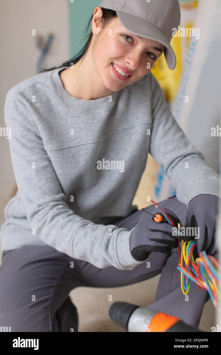 elettricista femmina che installa il dispositivo elettrico Foto Stock