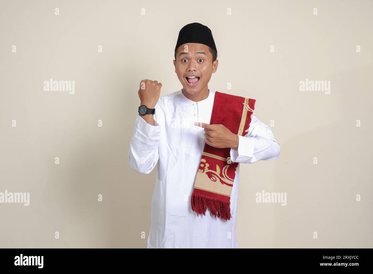 Ritratto di un attraente uomo musulmano asiatico in camicia bianca che guarda l'orologio da polso whille che punta con il dito. Immagine isolata su sfondo grigio Foto Stock