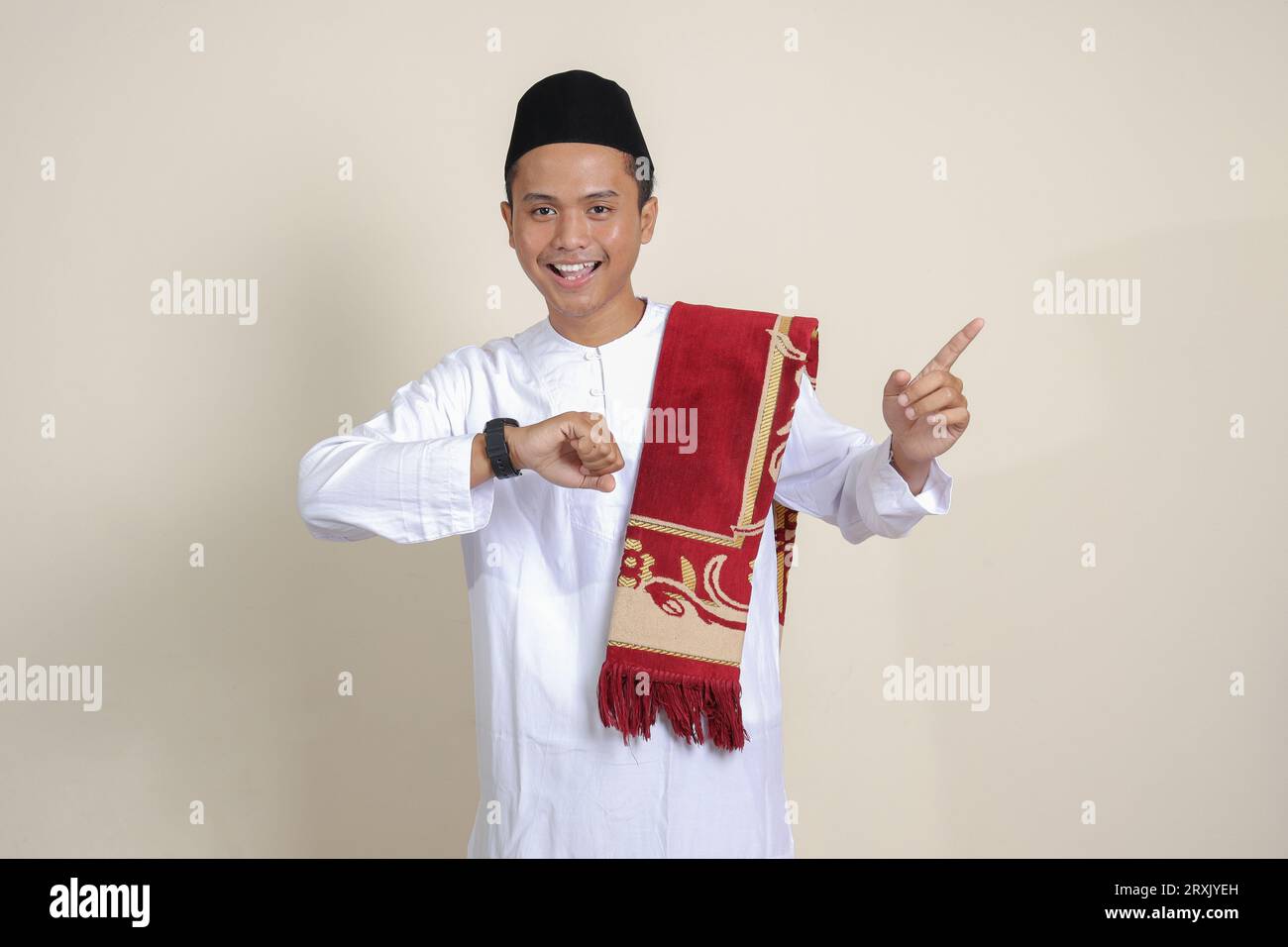 Ritratto di un attraente uomo musulmano asiatico in camicia bianca che guarda l'orologio da polso whille che punta con il dito. Immagine isolata su sfondo grigio Foto Stock