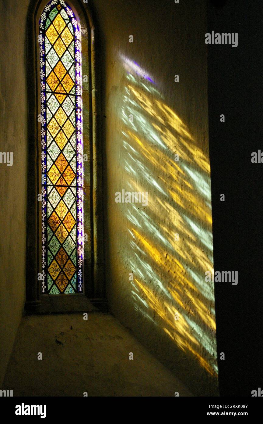 La luce del sole che fuma attraverso una vetrata colorata in una chiesa inglese. Foto Stock