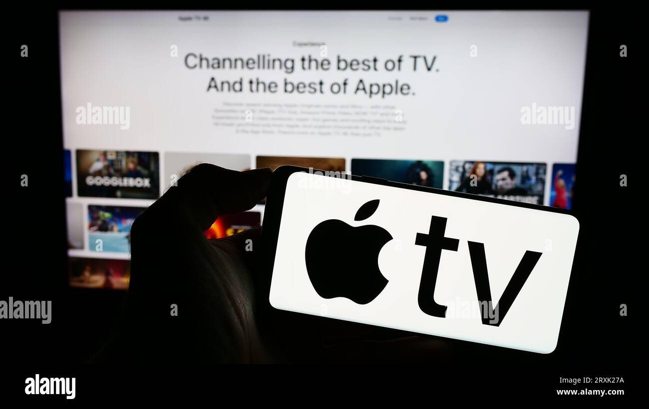 Persona che possiede il cellulare con il logo del servizio di streaming video Apple TV Plus sullo schermo davanti alla pagina Web aziendale. Concentrarsi sul display del telefono. Foto Stock