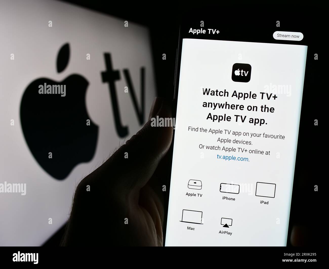 Persona che possiede il cellulare con una pagina Web del servizio di streaming video Apple TV Plus sullo schermo davanti al logo. Concentrarsi sul centro del display del telefono. Foto Stock