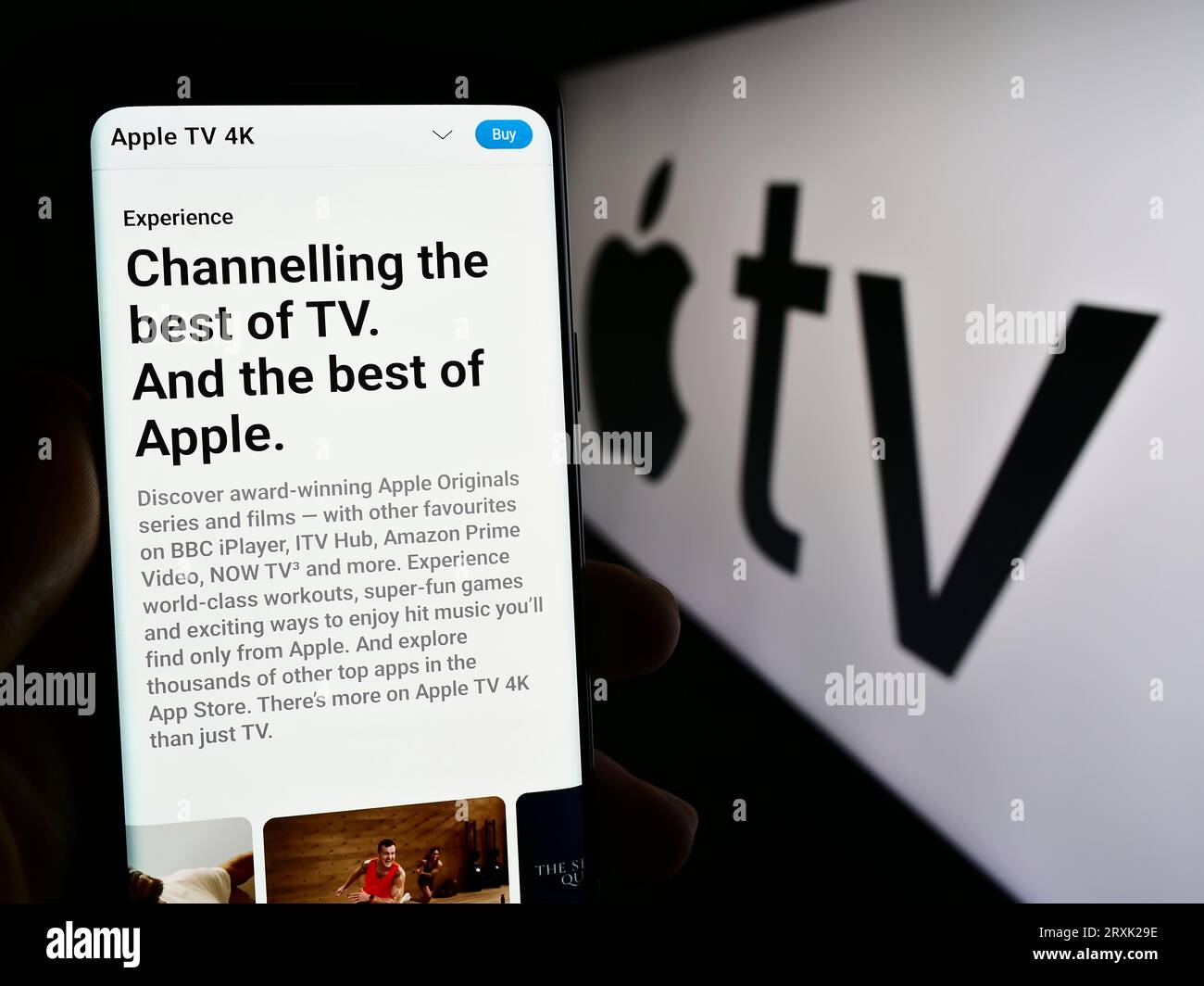 Persona che possiede uno smartphone con una pagina Web del servizio di streaming video Apple TV Plus sullo schermo davanti al logo. Concentrarsi sul centro del display del telefono. Foto Stock