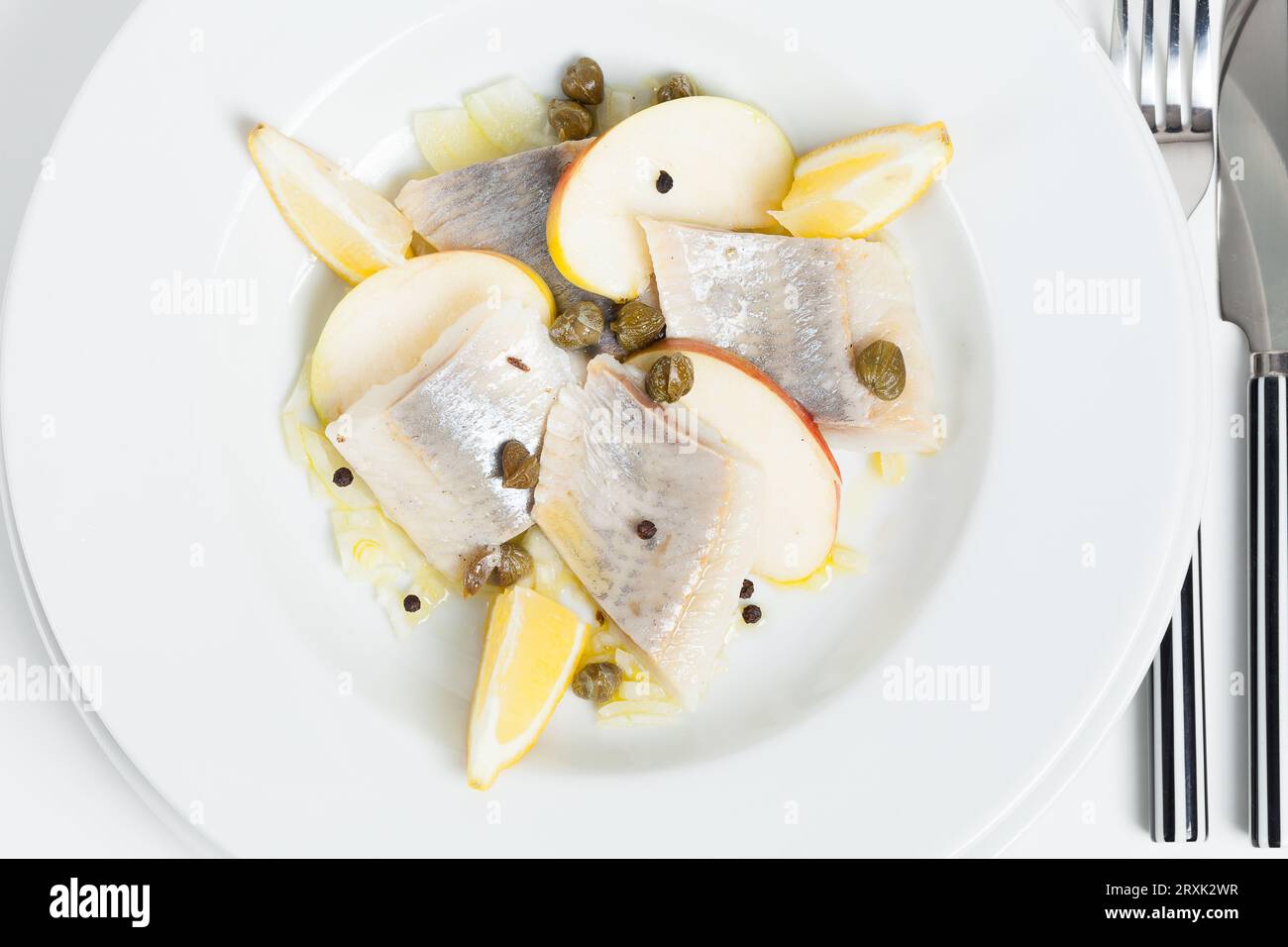 Aringa marinata al limone con mela e capperi in olio di lino. Foto Stock