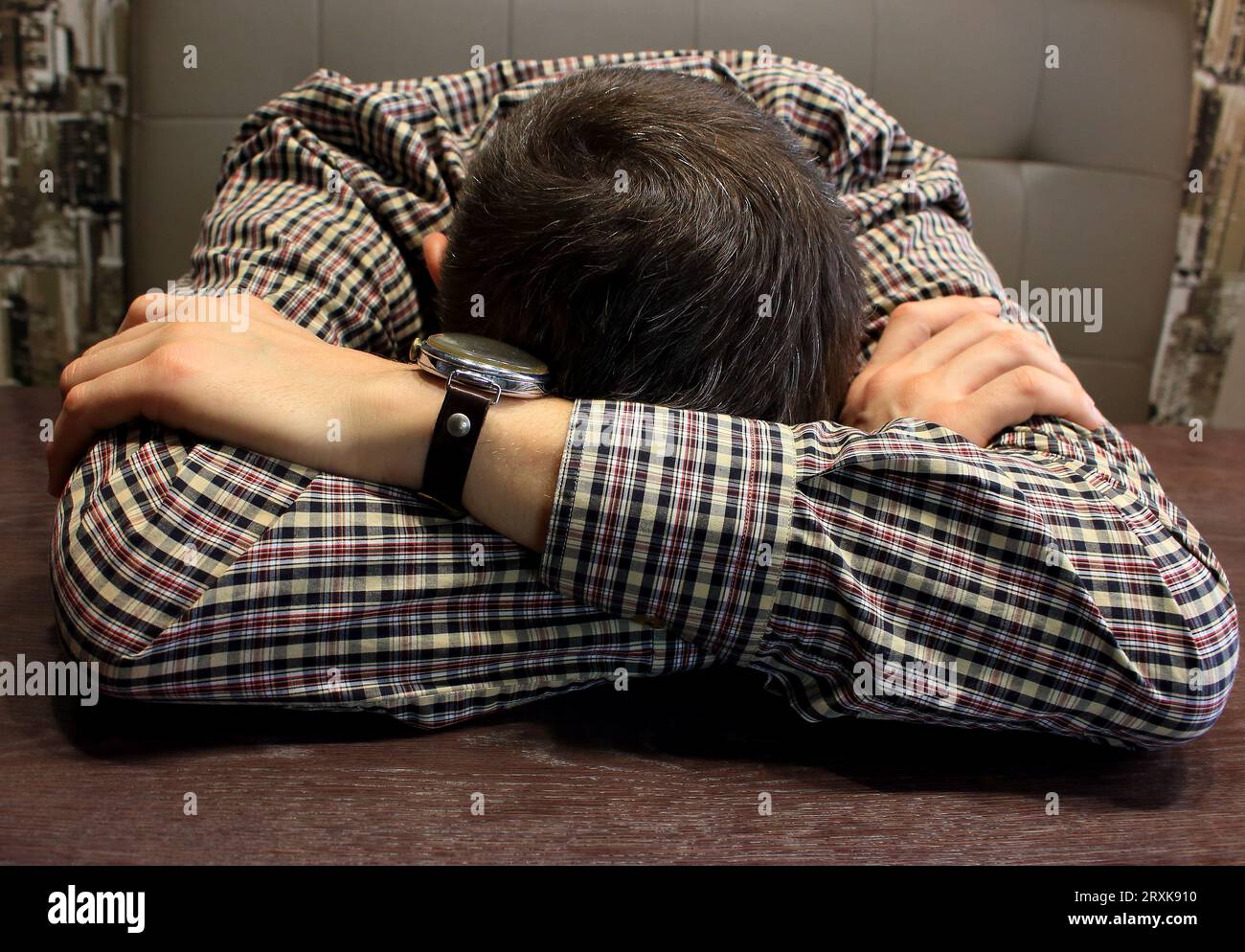 Uomo con la testa sulle mani a tavola. Sensazione di disperazione. Uomo esausto seduto in ufficio. Concetto di salute mentale. Foto Stock