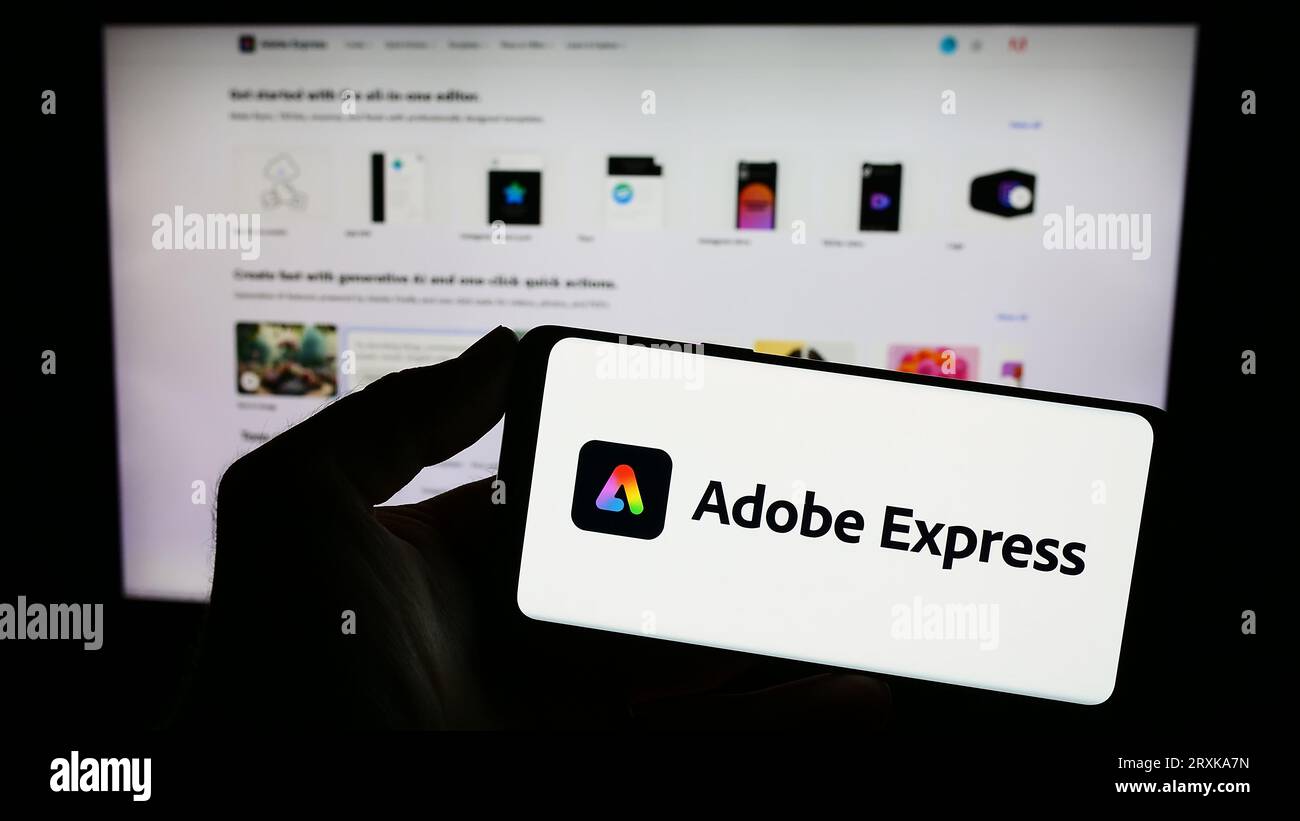 Persona che possiede un telefono cellulare con il logo del software di grafica Adobe Express sullo schermo davanti alla pagina Web dell'azienda. Concentrarsi sul display del telefono. Foto Stock