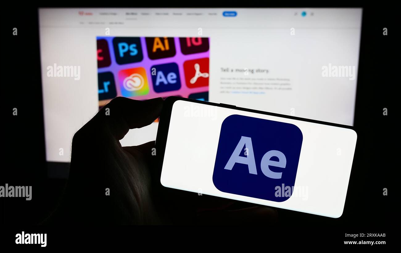 Persona che possiede un telefono cellulare con il logo del software di grafica animata Adobe After Effects sullo schermo davanti alla pagina Web. Concentrarsi sul display del telefono. Foto Stock