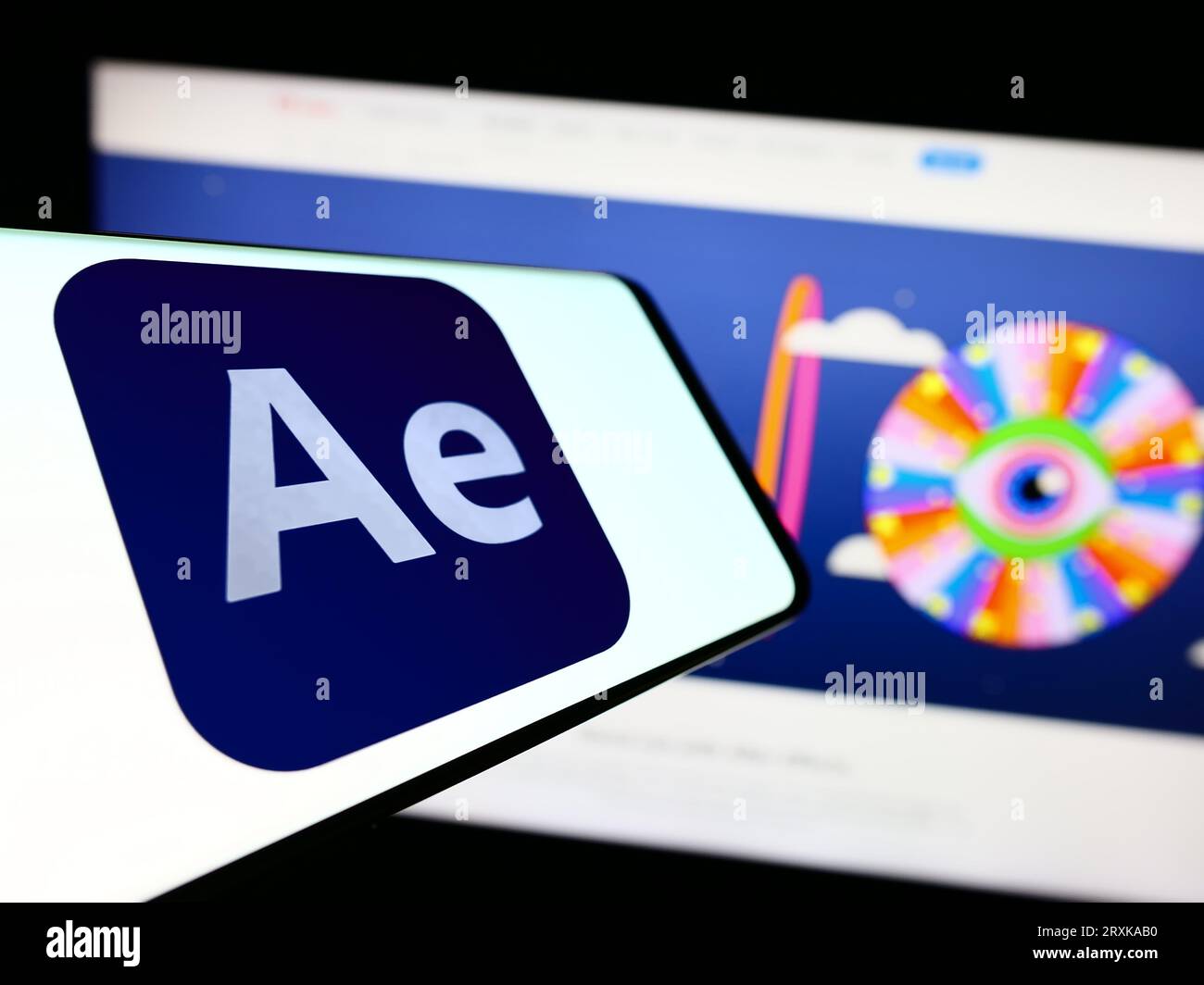 Telefono cellulare con logo del software di grafica animata Adobe After Effects sullo schermo di fronte al sito Web dell'azienda. Concentrarsi sul centro del display del telefono. Foto Stock