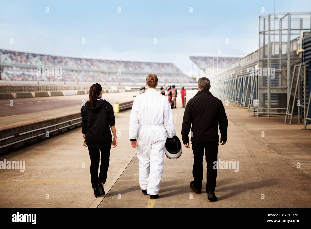 Tre persone che camminano verso il circuito con un senso di scopo e anticipazione. Foto Stock