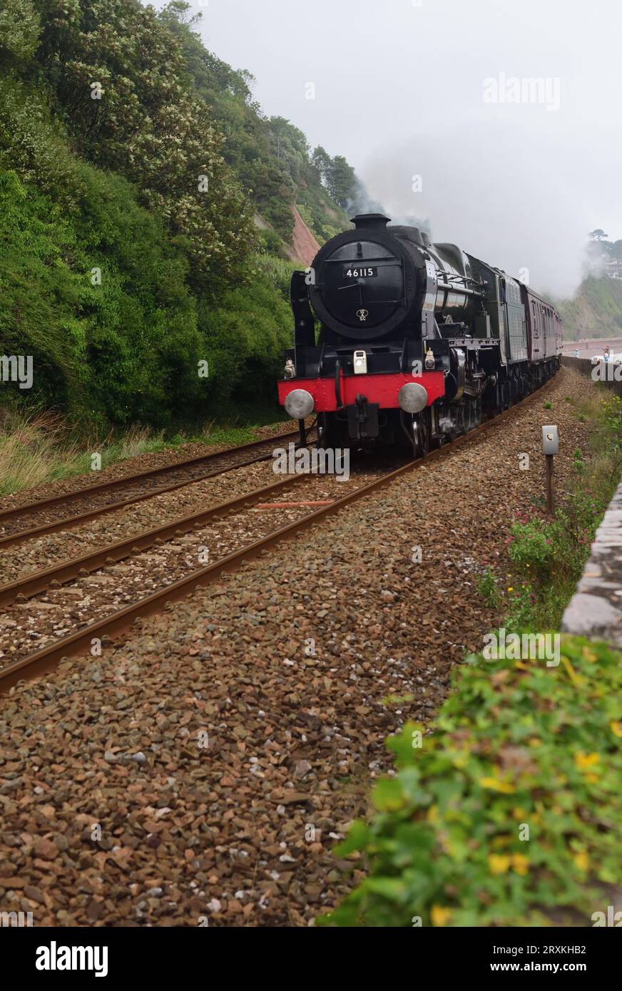 In un giorno coperto, la classe Royal Scot della LMS No 46115 Scots Guardsman corre lungo la diga di Teignmouth con il tour ferroviario del Royal Duchy. Foto Stock