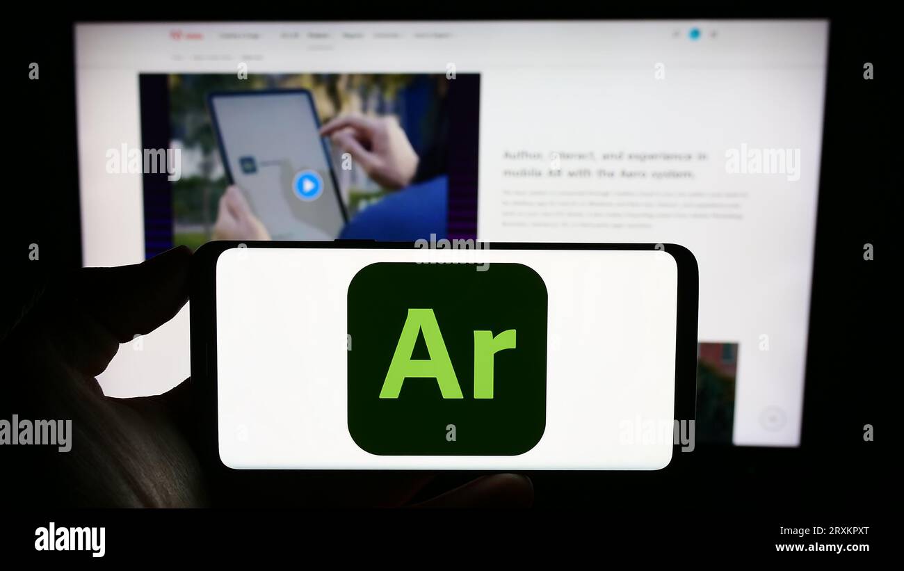 Persona che possiede un telefono cellulare con il logo del software di realtà aumentata Adobe Aero sullo schermo davanti alla pagina Web dell'azienda. Concentrarsi sul display del telefono. Foto Stock