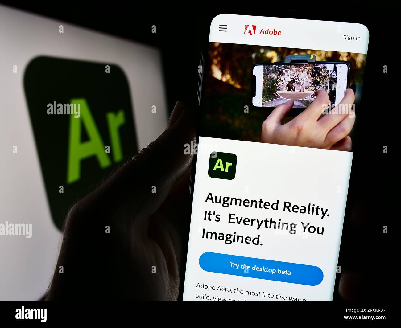 Persona che possiede il cellulare con una pagina Web del software di realtà aumentata Adobe Aero sullo schermo davanti al logo. Concentrarsi sul centro del display del telefono. Foto Stock