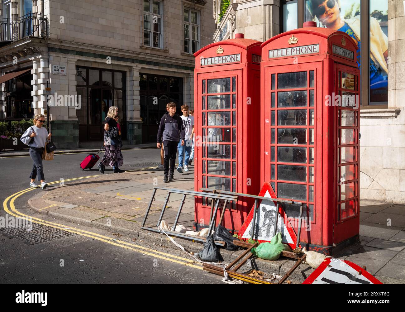 Due cabine telefoniche rosse sbiadite e fatiscenti, ma ancora funzionanti, accanto ai cartelli stradali a Piccadilly, nel centro di Londra, nel Regno Unito. Foto Stock