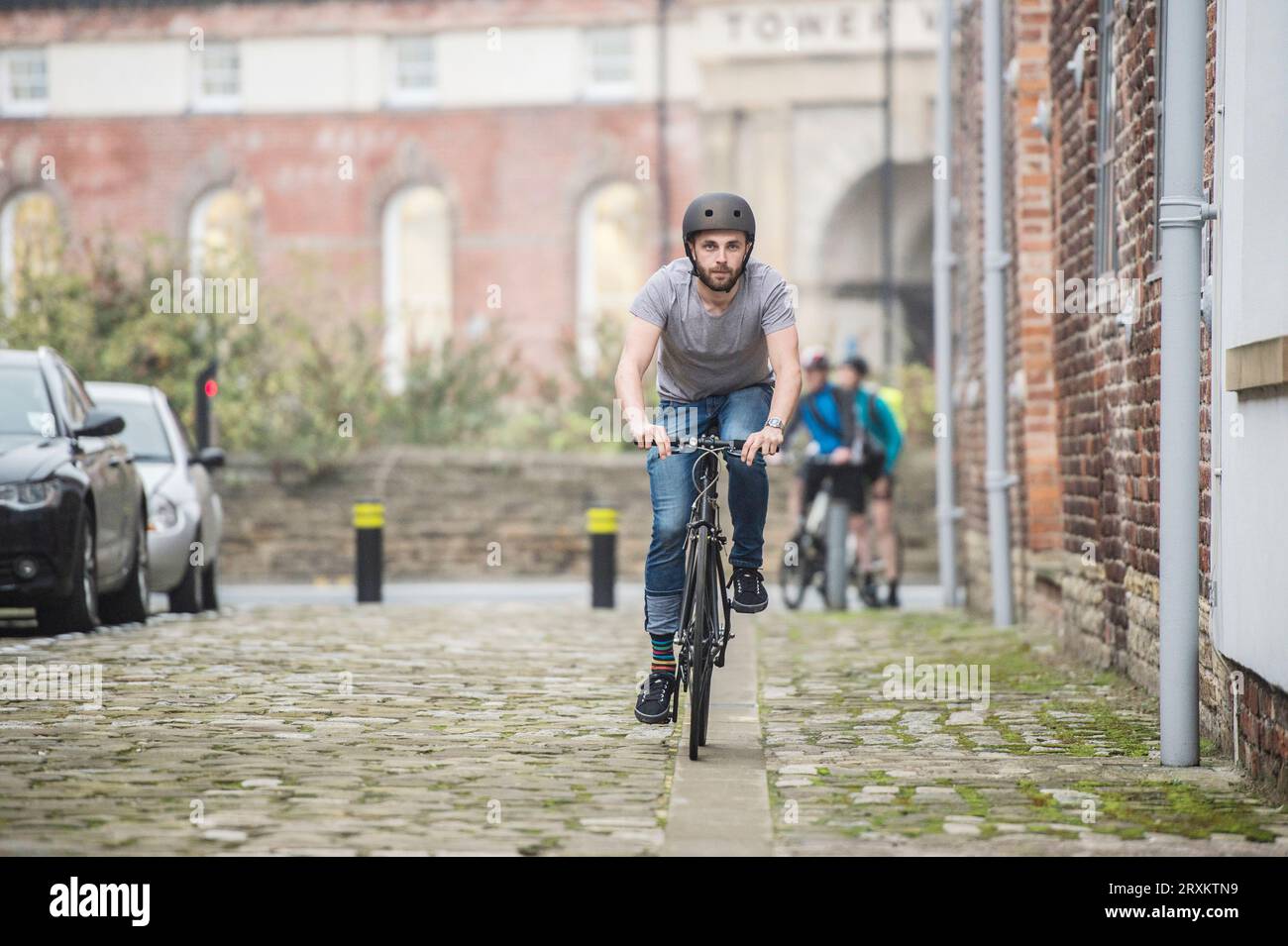 L'uomo gli spostamenti in bicicletta lungo una strada di città Foto Stock