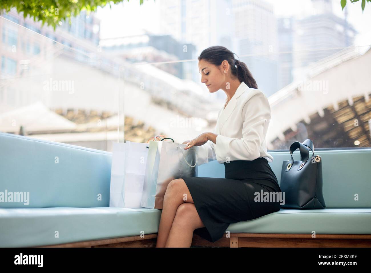 Donna d'affari con le borse della spesa sul divano Foto Stock
