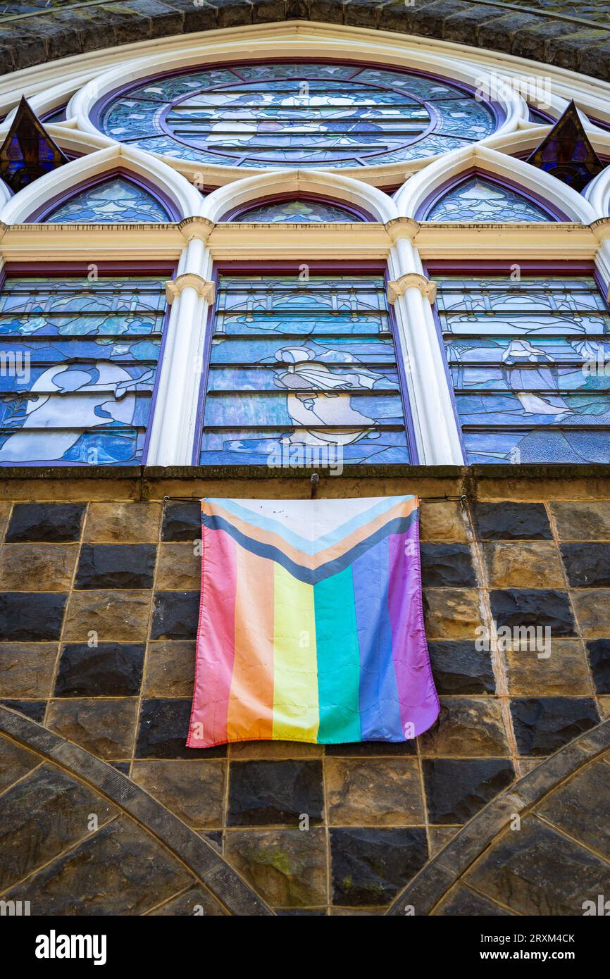 Bandiera di orgoglio appesa sotto una vetrata colorata sul davanti di una chiesa nel centro di Portland, Oregon Foto Stock