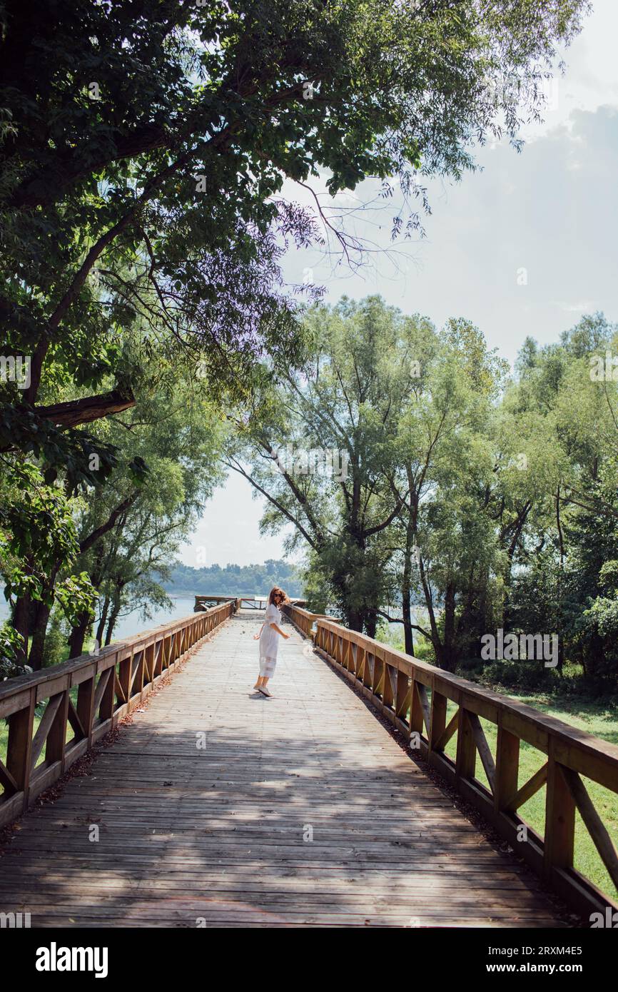 Donna che cammina sul lungomare vicino agli alberi Foto Stock