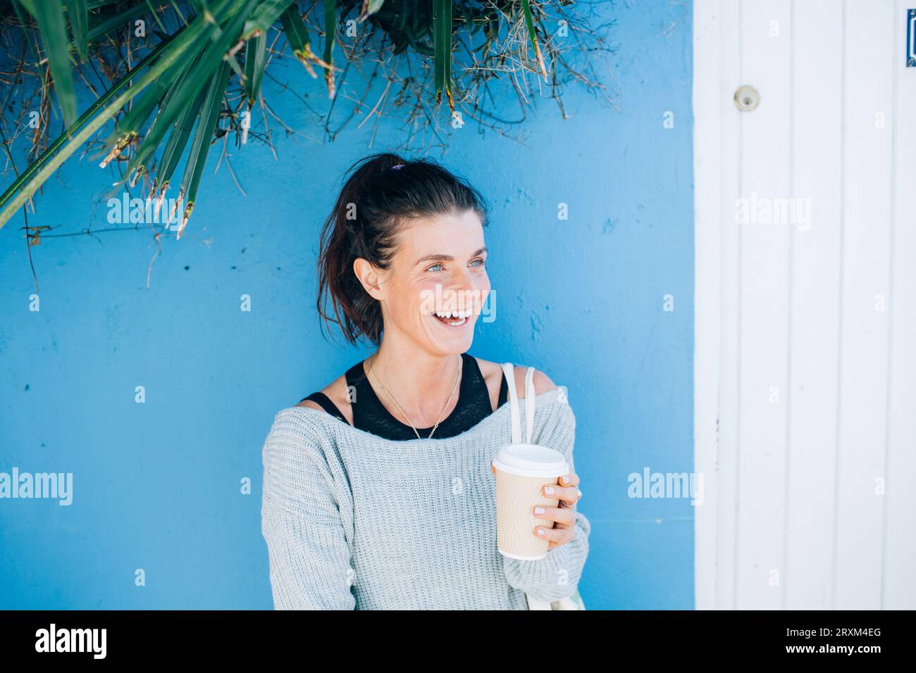 Sorridente donna adulta che tiene una tazza di caffè da asporto Foto Stock