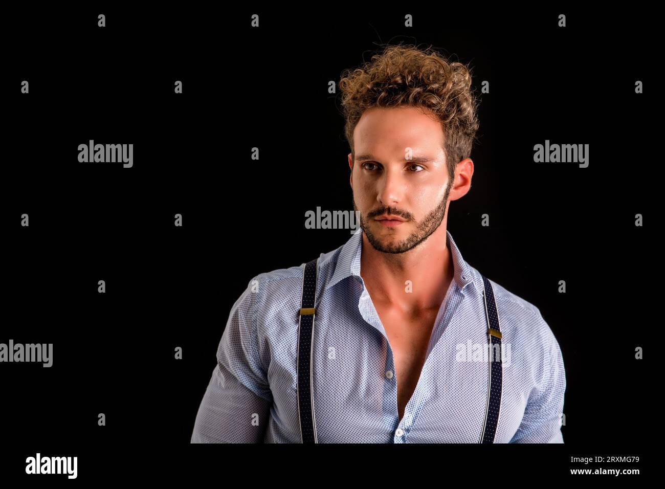 Un uomo che indossa dei parapetti e una camicia blu Foto Stock