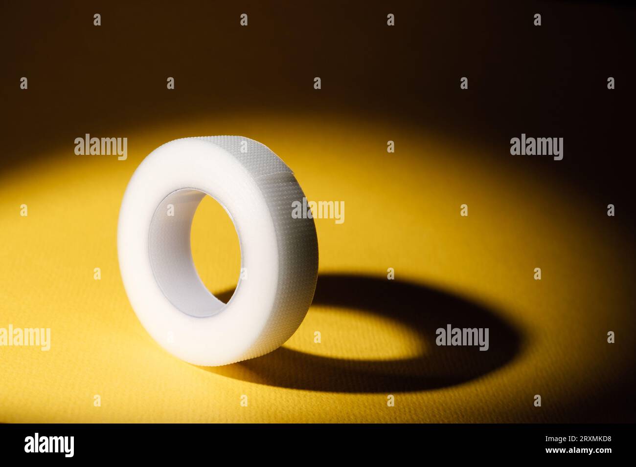 Nastro terapeutico elastico per cosmetologia e medicina. Rotolo di nastro bianco su sfondo giallo. Industria della bellezza e della moda. Nastro Kinesio. Beaut Foto Stock