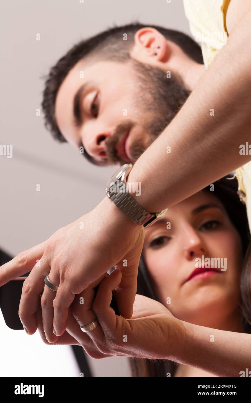 Uomo e donna vicini. E' al telefono, ignorando i suoi segnali di frustrazione. Questi dispositivi, anche se innegabilmente utili, portano isolamento e maleducazione Foto Stock