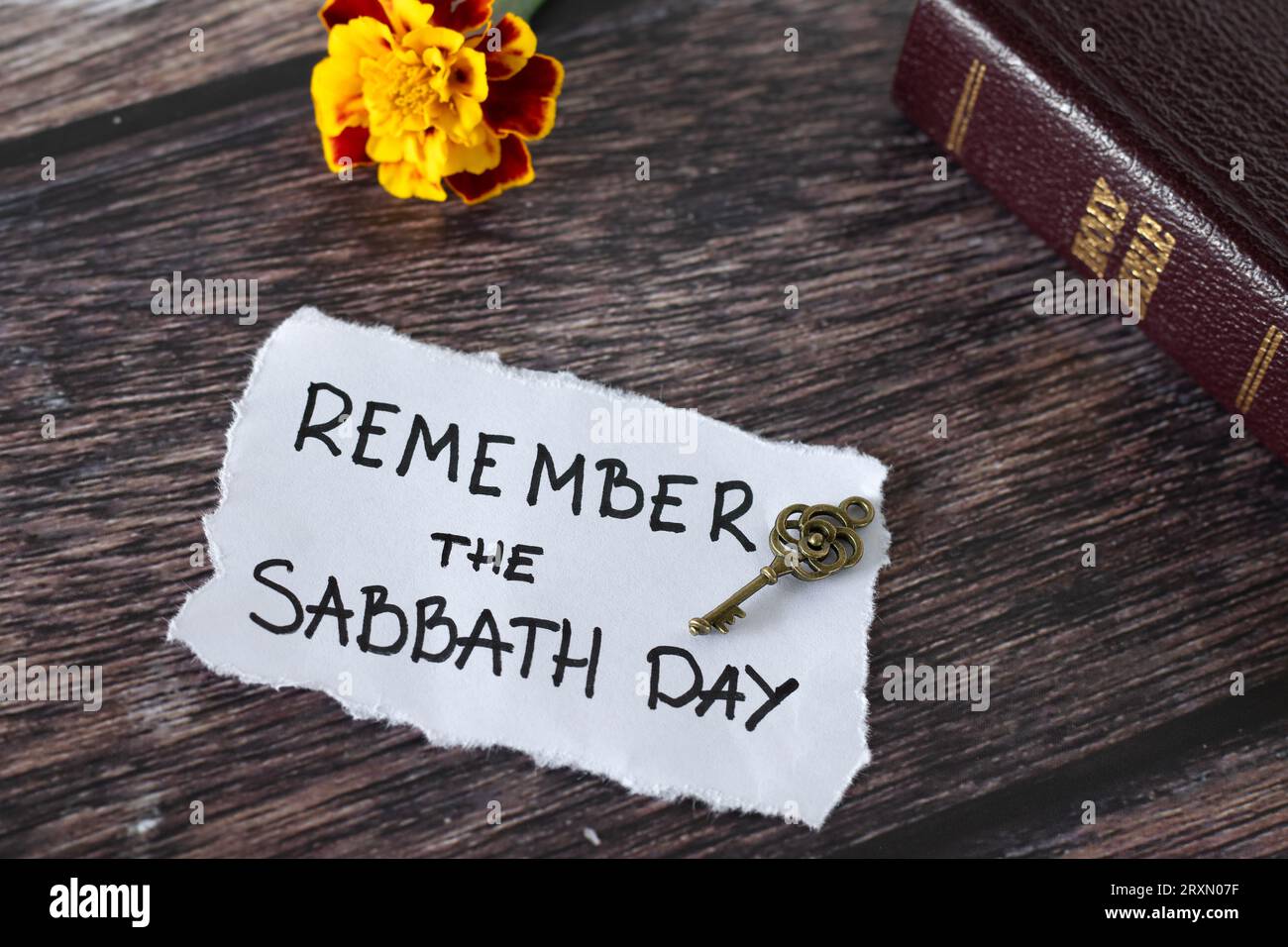 Ricorda il giorno dello Shabbat, citazione scritta a mano con chiave antica, Sacra bibbia e fiore su legno. Riposo biblico, obbedienza cristiana a Dio Gesù Cristo. Foto Stock