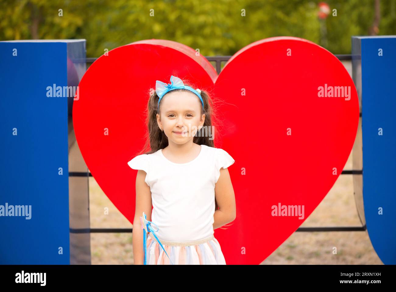 Ritratto di ragazza caucasica davanti a un simbolo di legno a forma di cuore rosso Foto Stock