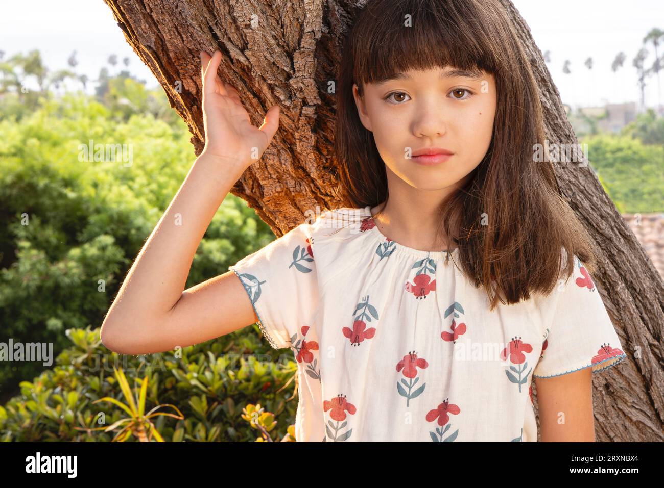 Bambina di undici anni appoggiata contro un albero Foto Stock