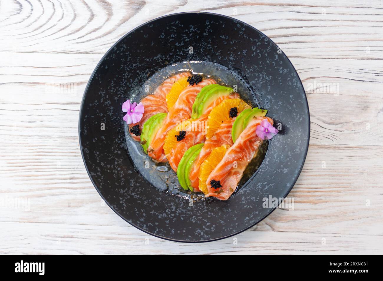 Ceviche di salmone con salsa di avocado, arancia e mango su uno sfondo di legno chiaro Foto Stock