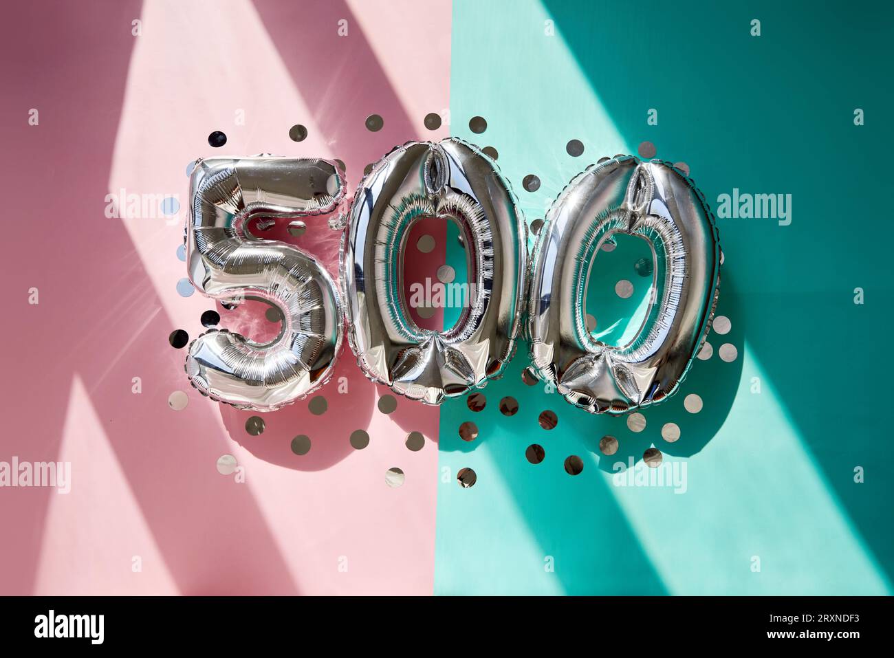 Numeri argento 500 cinquecento palloncini Sunlight sfondo rosa turchese Foto Stock
