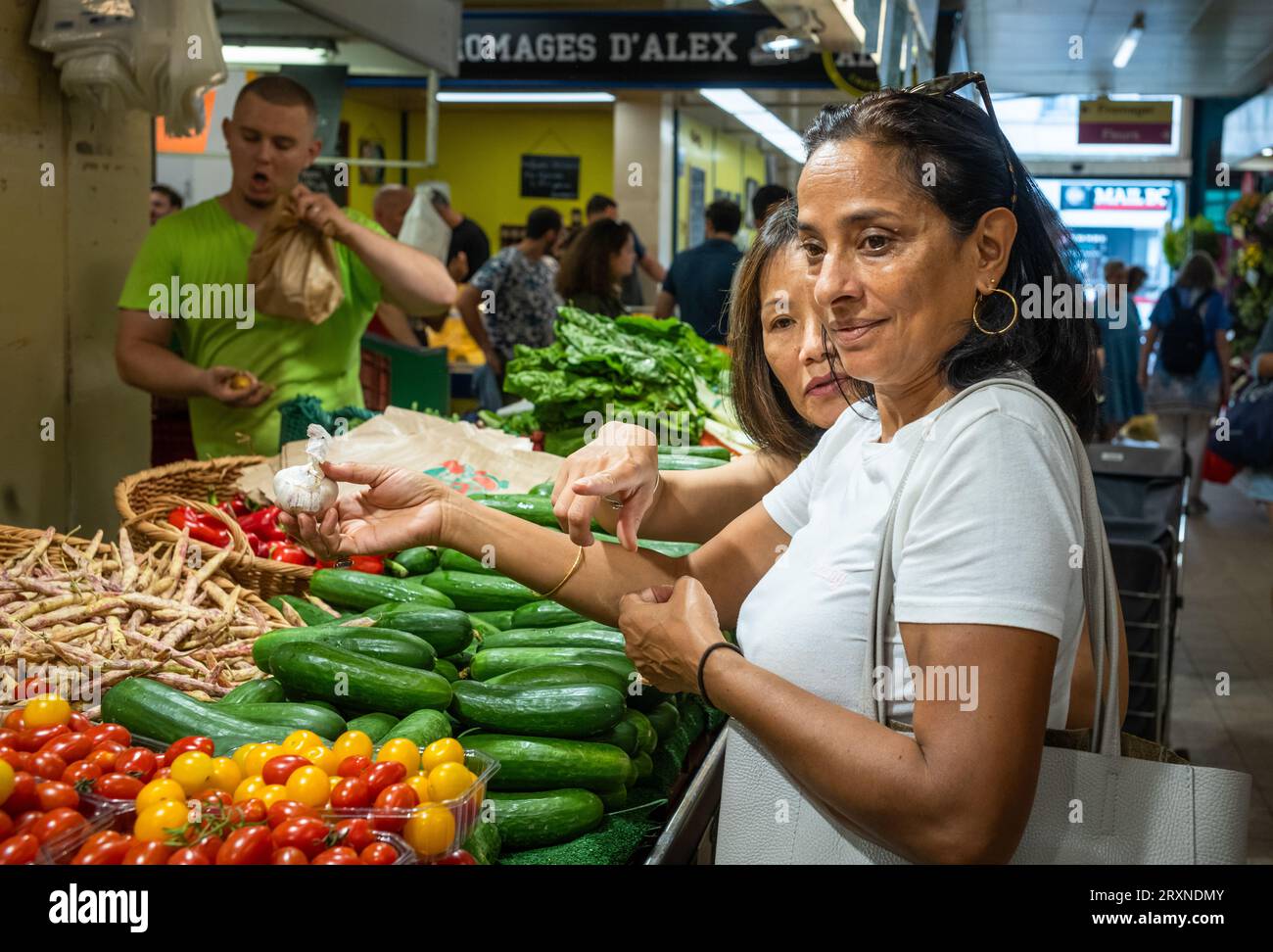 Le donne comprano aglio e altre verdure in una bancarella al mercato interno di Montrouge, nei sobborghi di Parigi, in Francia. Foto Stock