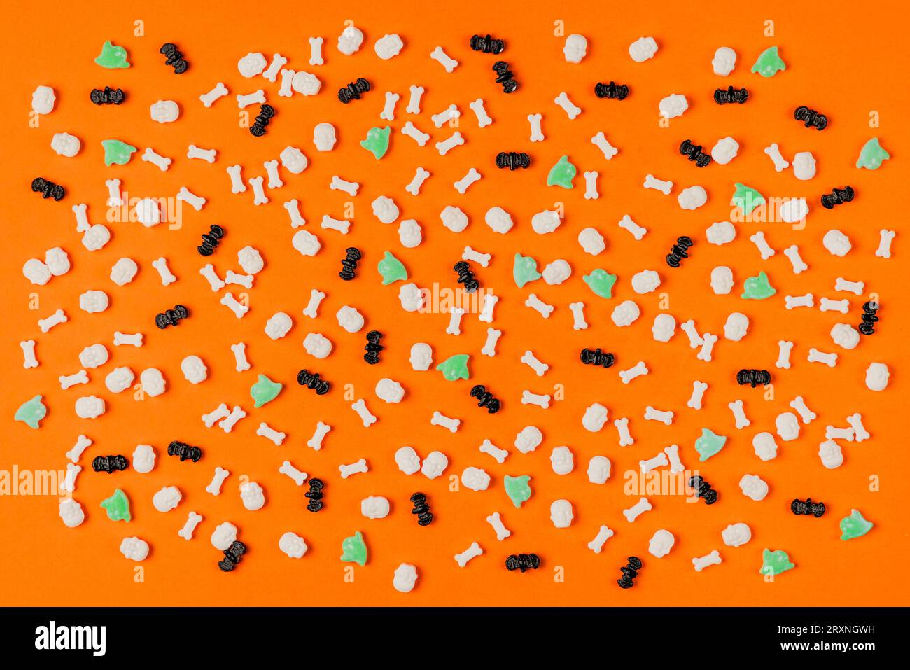 Sfondo di Halloween, pipistrelli, teschi e ossa in bianco, fantasmi in verde su arancione Foto Stock