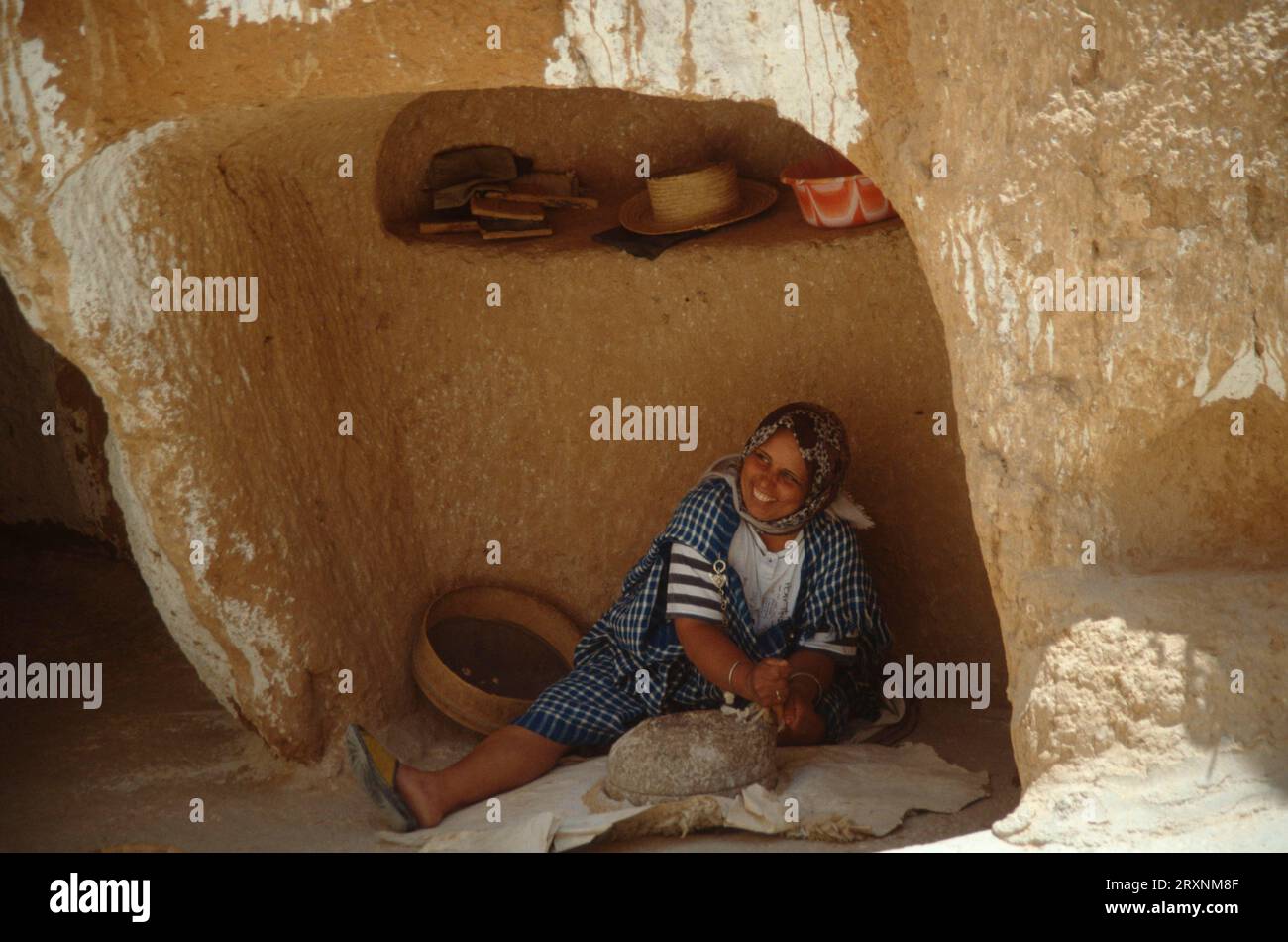 Donna in alloggio in grotta granturco macinato, /, villaggio di Barbary Matmata, Tunisia, donna in alloggio in grotta macina granturco, insediamento berbero Matmata, Tunisia Foto Stock