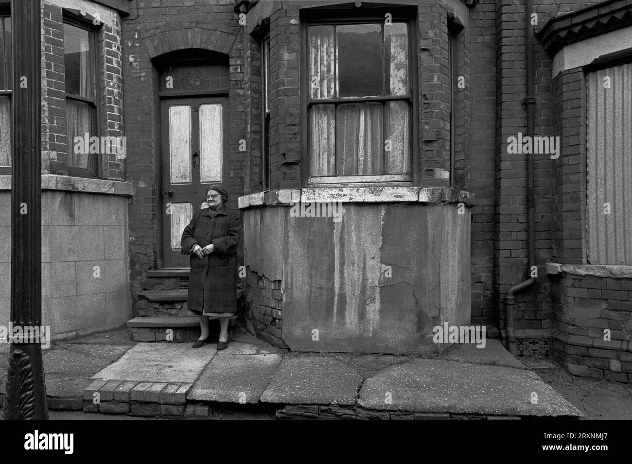 La signora anziana si trovava di fronte alla sua casa vittoriana a schiera, in attesa di essere demolita durante la slum di St Ann's, Nottingham, Inghilterra. Foto Stock