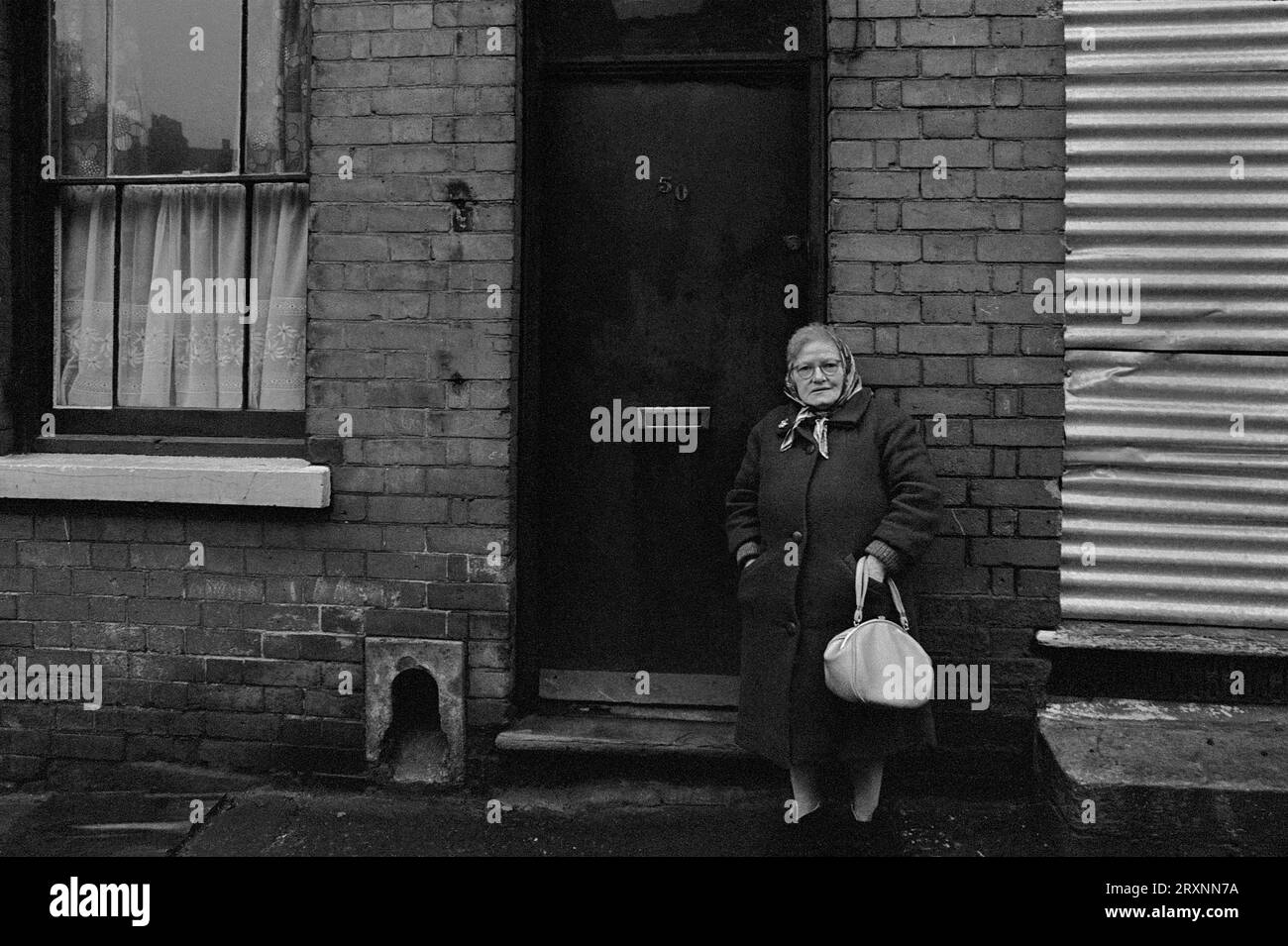 La signora anziana si trovava di fronte alla sua casa vittoriana a schiera, in attesa di essere demolita durante la slum di St Ann's, Nottingham, Inghilterra. Foto Stock