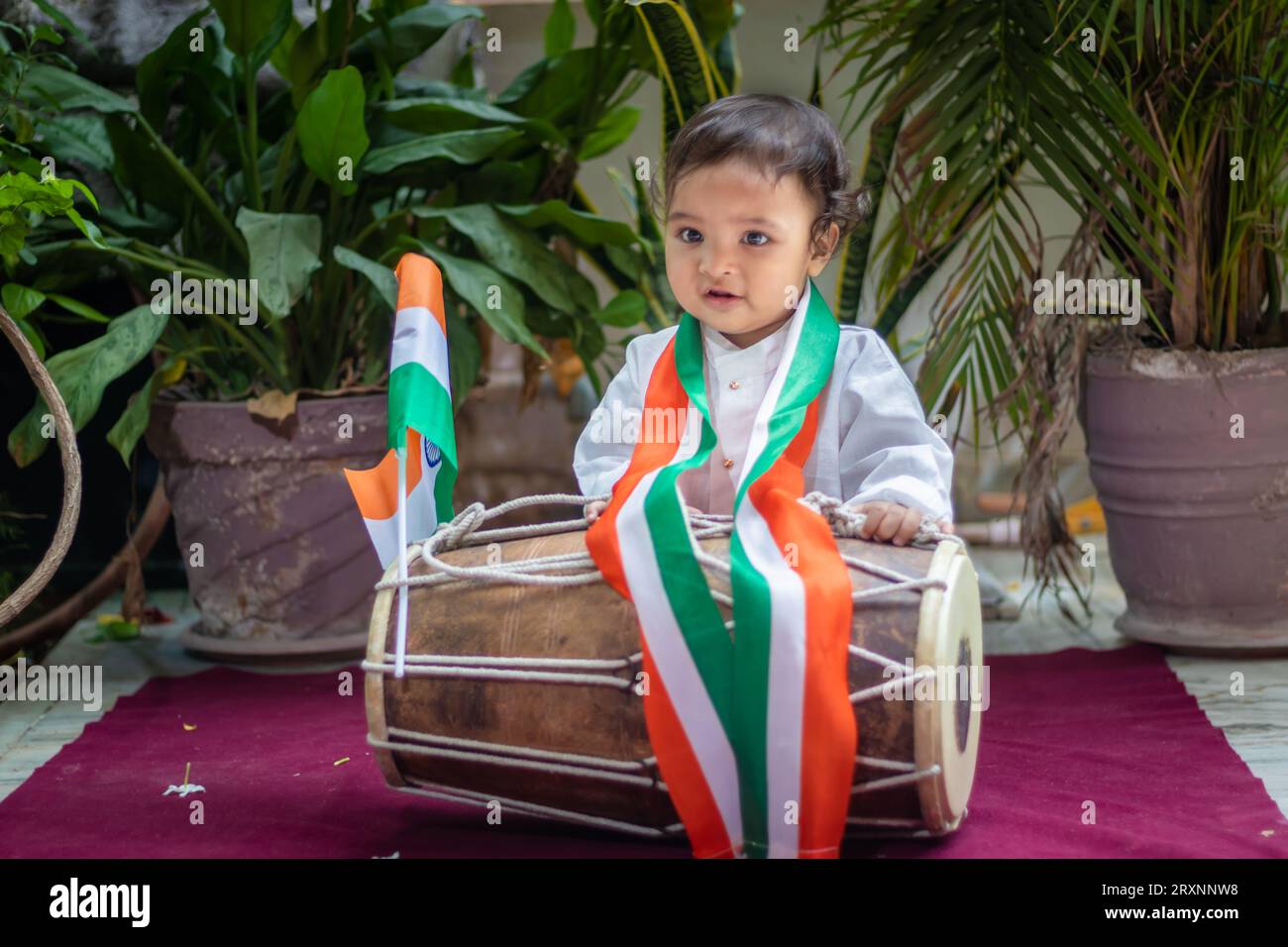 simpatico bimbo con bandiera tricolore indiana con dholak tradizionale e un panno con viso innocente Foto Stock