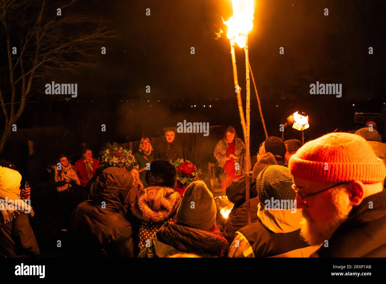 Tradizionale cerimonia di wassailing con torce fiammeggianti e comunità riunita nel frutteto del Somerset di notte Foto Stock