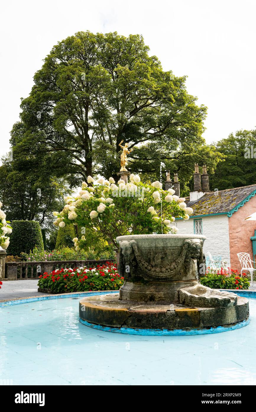 Fontana ornata in pietra con ortensie bianche nella pittoresca piazza del villaggio gallese Foto Stock