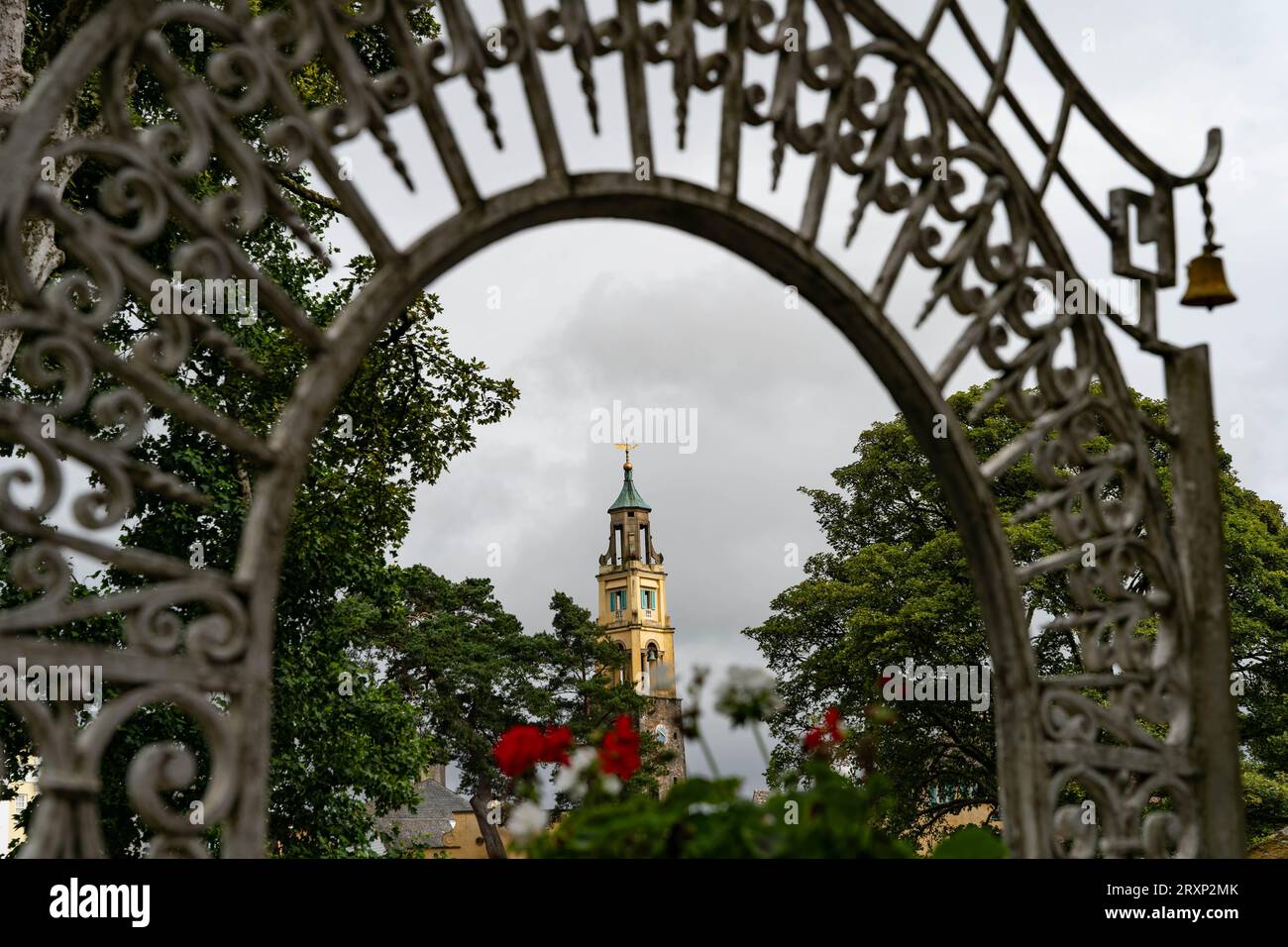 Arcata di ferro ornata che incornicia lo storico campanile del villaggio di Portmeirion, Galles Foto Stock