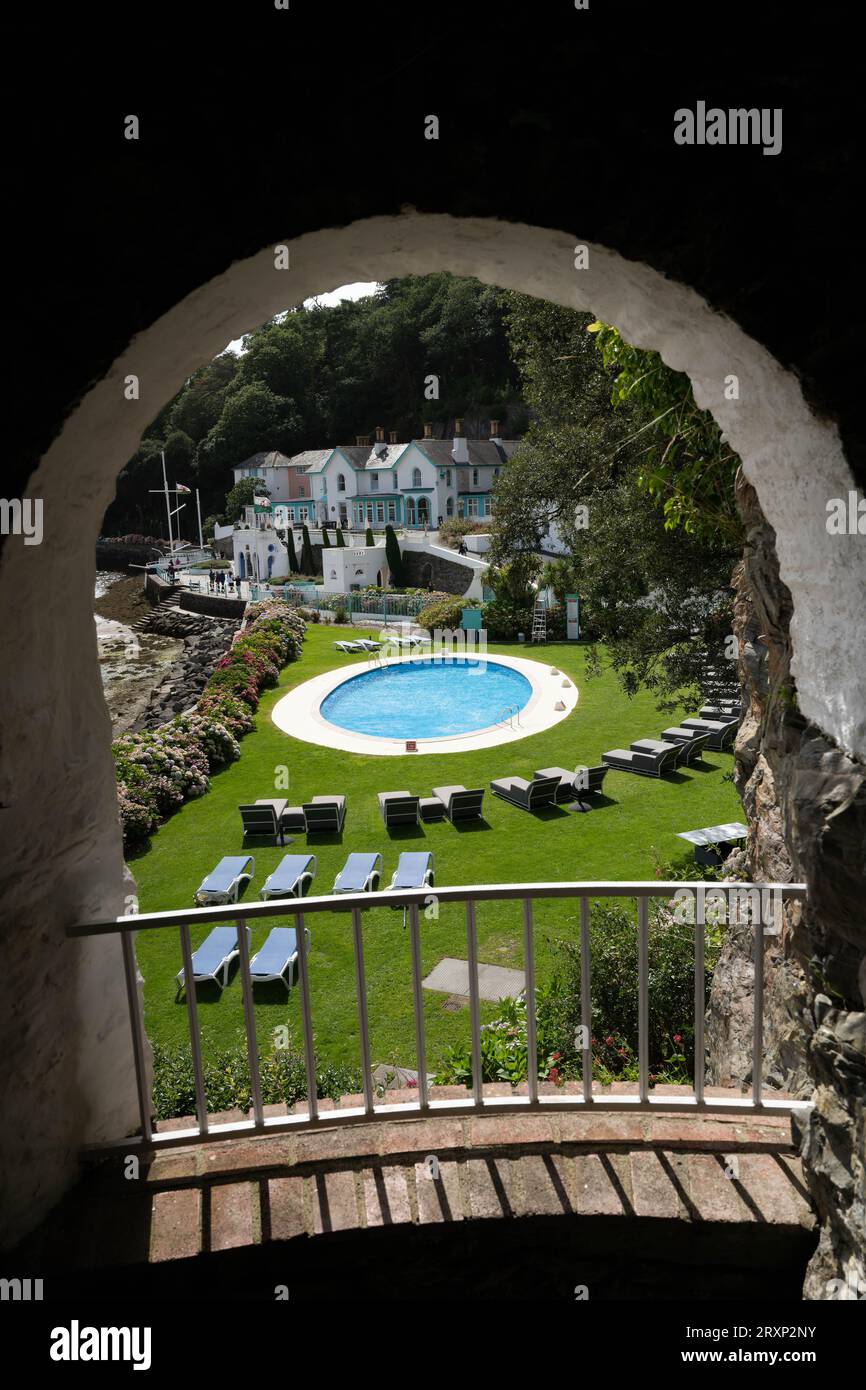 Vista attraverso l'arco in pietra della piscina e degli edifici colorati del resort Portmeirion Foto Stock