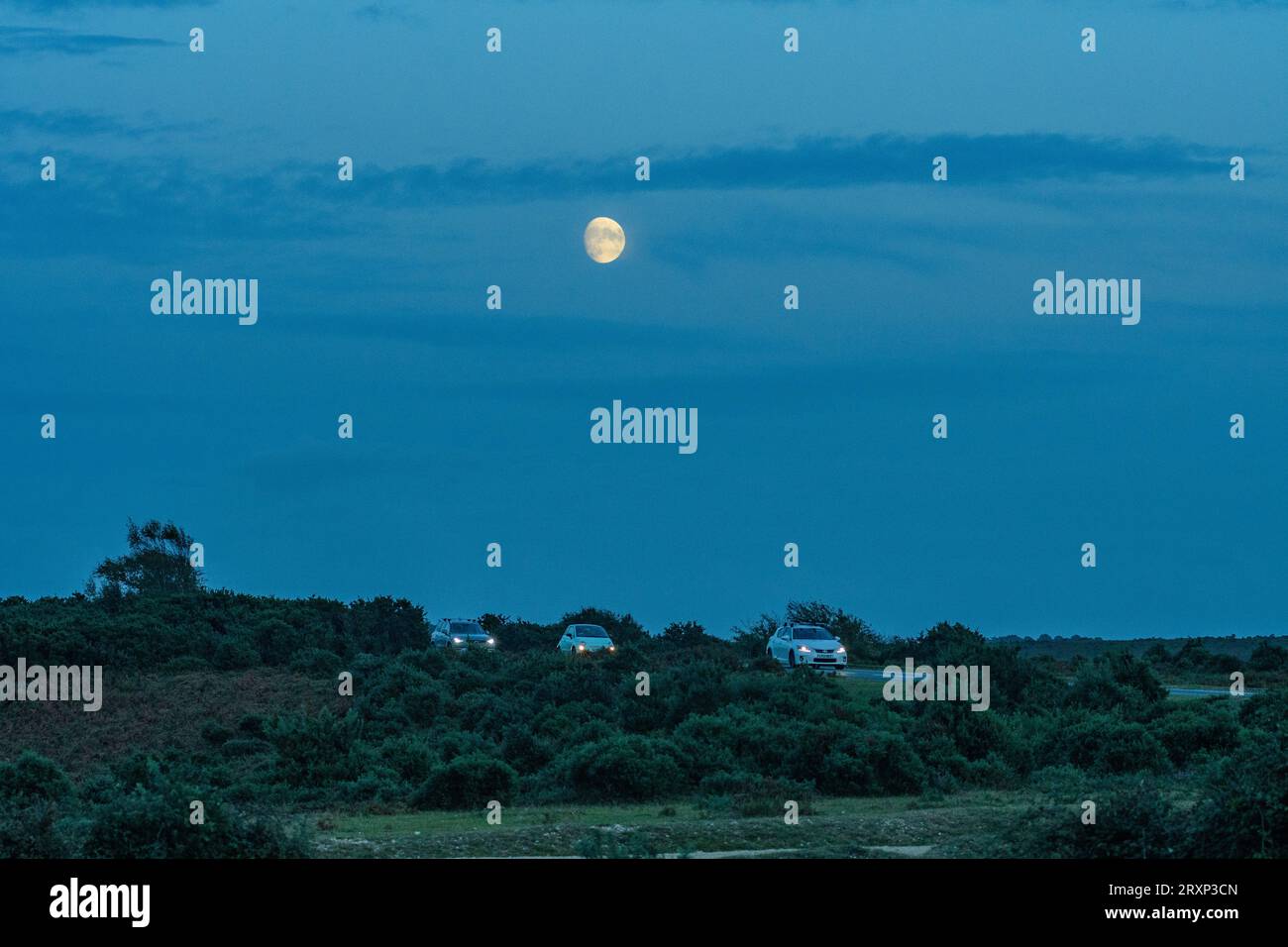 Deadman Corner, Godshill, New Forest, Hampshire, Inghilterra, Regno Unito, 26 settembre 2023: meteo. La luna sorge al crepuscolo sopra il traffico pendolare dopo un'altra calda giornata autunnale. Crediti: Paul Biggins/Alamy Live News Foto Stock