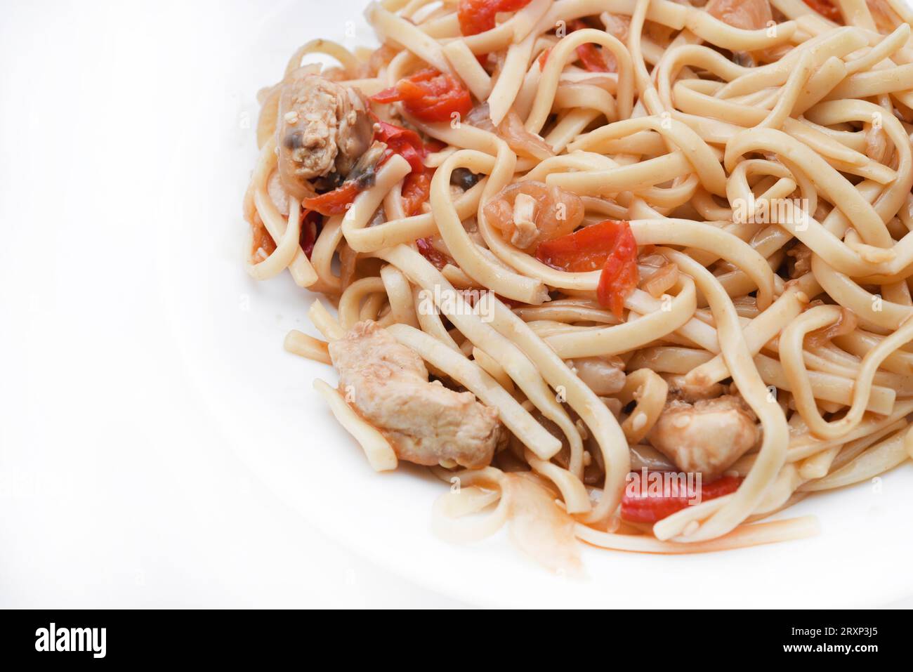 Tagliatelle coreane Udon con carne su un piatto bianco. Deliziosa colazione a base di carne piccante. Foto Stock